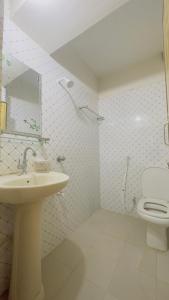 La salle de bains blanche est pourvue d'un lavabo et de toilettes. dans l'établissement Hotel Royal Blue Residence, à Dhaka