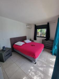1 dormitorio con cama roja y ventana en La Villa Boussole 2, en Saint-Leu