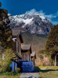 a house with a snow covered mountain in the background at The Rock Hotel in Lijiang