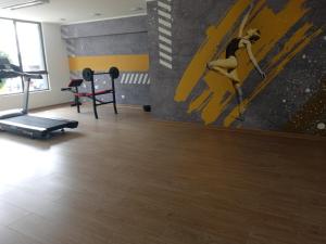 - une salle de sport avec un tapis de course et un tableau mural dans l'établissement DEPARTAMENTO ARAUCO CENTRO CHILLAN Con ESTACIONAMIENTO, à Chillán