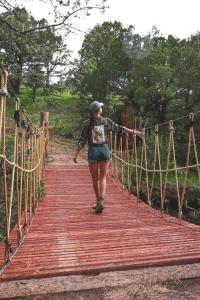 a woman walking across a wooden suspension bridge at Silver Bullet Airstream, El Mistico Glamping Ranch in Nogal