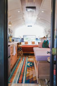 Silver Bullet Airstream, El Mistico Glamping Ranch في Nogal: مطبخ صغير مع أريكة وسرير