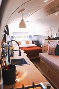 Silver Bullet Airstream, El Mistico Glamping Ranch في Nogal: مطبخ مع حوض في غرفة مع سرير