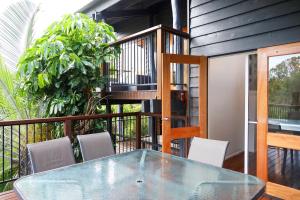 a glass table and chairs on a balcony at The Treehouse in Airlie Beach