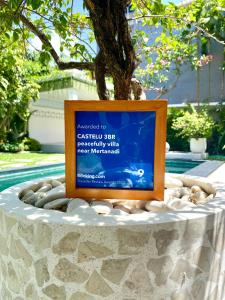 a sign sitting on top of a table next to a tree at CASTELU 3BR peacefully villa near Mertanadi in Seminyak