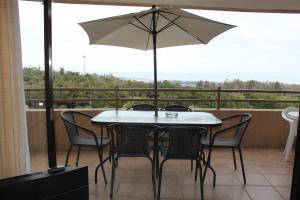 a table and chairs with an umbrella on a balcony at Departamentos Mednav Mantagua in Concón