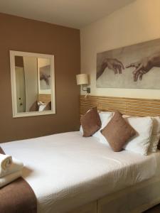 een slaapkamer met een groot wit bed en 2 spiegels bij Dockside Hotel in Londen