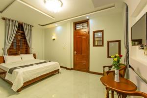 a bedroom with a bed and a table and a door at Phuong Trang Villa Hoi An in Hoi An