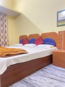 バラナシにあるShivalay paying guest houseのベッドルーム1室(大型木製ベッド1台、赤い枕付)