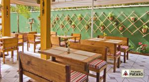 a restaurant with wooden tables and chairs and a green wall at Pousada Pataxó in Ubatuba