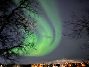 uma aurora no céu sobre uma cidade em Beijing home em Tromsø