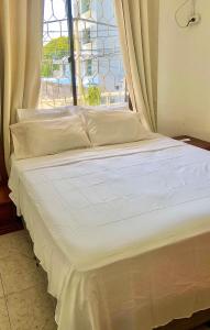uma cama branca com uma janela num quarto em Acogedor apartamento en bruselas em Cartagena das Índias