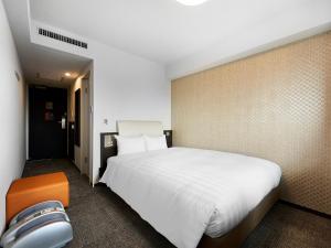 川崎市にあるダイワロイネットホテル川崎のベッドルーム(大きな白いベッド1台、オレンジの椅子付)
