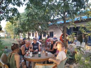 un grupo de personas sentadas en una mesa bajo un árbol en Vimeanz @Bohemiaz, en Kampot