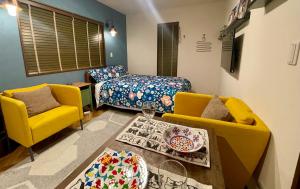 een woonkamer met 2 gele stoelen en een bed bij Kiwi House Tokoname VACATION STAY in Tokoname