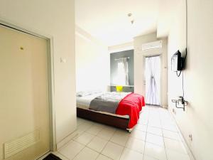 um quarto com uma cama com um cobertor vermelho e uma janela em RedLiving Apartment @ Dramaga Tower by Liana Room em Bubulak 3