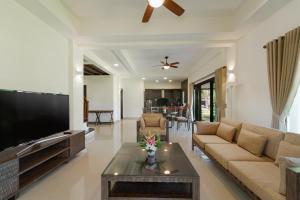 ein Wohnzimmer mit einem großen TV und einem Sofa in der Unterkunft Banyu Biru Villa in Lagoi