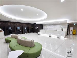 a lobby with a green couch andools in a building at Daiwa Roynet Hotel Kawasaki in Kawasaki