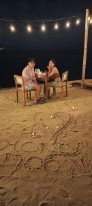 two people sitting at a table on the beach at Villa Penyu Gili Trawangan in Gili Trawangan
