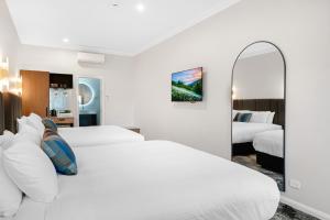 two beds in a hotel room with a mirror at St Hugh Hotel Wagga Wagga in Wagga Wagga