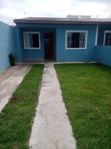 a blue house with a grass yard in front of it at casa de praia em Matinhos in Matinhos