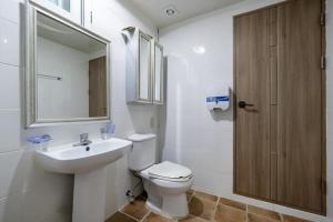 ein Badezimmer mit einem WC, einem Waschbecken und einem Spiegel in der Unterkunft Yongmaru Pension in Suncheon