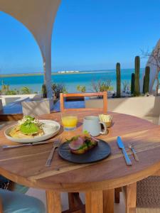 a wooden table with a plate of food on a table with the beach at Republica Pagana - Only Adults in La Paz +41 photos