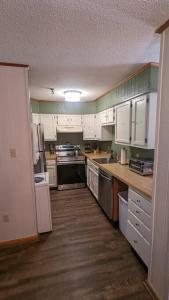 史諾修的住宿－Evergreen Escape At Snowshoe，厨房铺有木地板,配有白色橱柜。