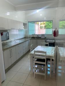 a kitchen with white cabinets and a table with chairs at Casa em Peruíbe in Peruíbe