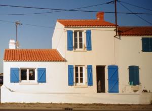 a white house with blue shutters at La cousinade No in Noirmoutier-en-l'lle