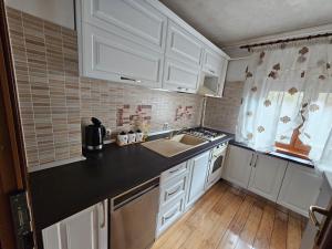a kitchen with white cabinets and a black counter top at Apartament 3 camere plus living, 2 bai, modern in Craiova