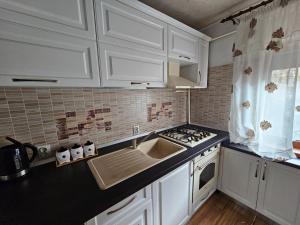 a kitchen with white cabinets and a sink and a stove at Apartament 3 camere plus living, 2 bai, modern in Craiova +15 photos