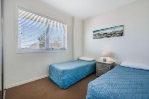a bedroom with two beds and a window at Pandanus Court in Caloundra
