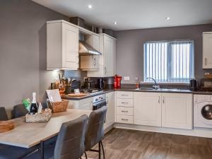 a kitchen with white cabinets and a table with chairs at The Gainsborough Mews in Gainsborough