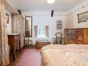 a bedroom with a bed and a dresser and a desk at Gore Cottage in Powerstock