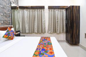 a bedroom with a bed with a colorful blanket on it at FabHotel Sriya in Durgāpur