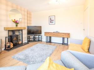 uma sala de estar com um sofá e uma televisão em Colbheinn Cottage em Brora