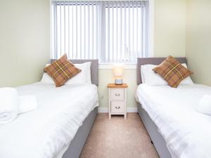 2 camas individuales en una habitación con ventana en Colbheinn Cottage, en Brora