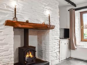 a stone fireplace with a wood stove in a room at Winsbeer Cottage in Buckland Monachorum