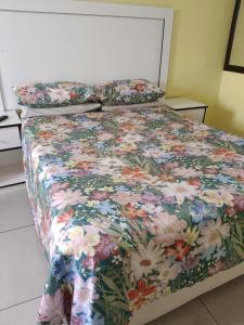 a bed with a floral bedspread and pillows on it at AGNES GUEST HOUSE in Germiston