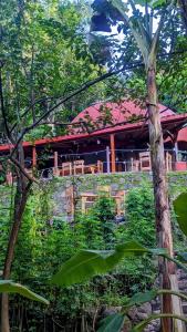 um edifício com um telhado vermelho atrás de algumas árvores em Wood Cabin - Cabana Maderas em Balgue