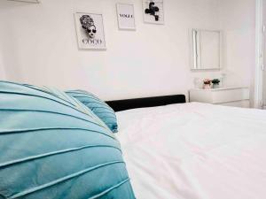 a white bed with blue pillows in a bedroom at Iconic location only 500 meters to The Louvre in Paris