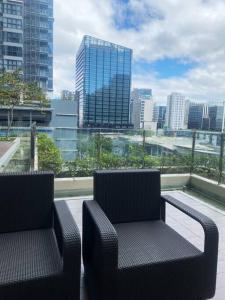 two chairs on a balcony with a view of a city at Uptown Stays+ Free pool access & Building views in Manila