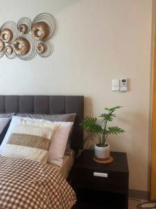 a bedroom with a bed and a plant on a table at Uptown Stays+ Free pool access & Building views in Manila