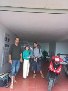 un groupe de trois personnes debout à côté d'une moto dans l'établissement HAI DANG HOTEL, à Xóm Ðé