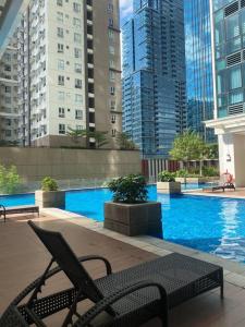 a blue swimming pool in a city with tall buildings at Uptown Stays+ Free pool access & Building views in Manila