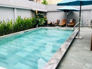 a swimming pool with an umbrella and chairs at Phuong Trang Villa Hoi An in Hoi An