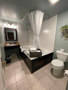 a bathroom with a tub and a toilet and a sink at Kalispell Grand Hotel in Kalispell