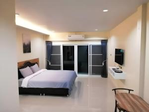 a bedroom with a white bed and a television at Triple J Hometel in Bang Tao Beach