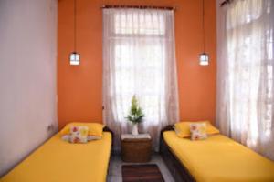 迪馬普爾的住宿－Trinity Villa Dimapur，橙色墙壁客房的两张床